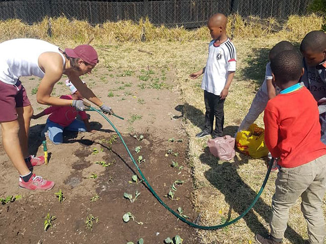Freiwilliger baut zusammen mit Kindern Gemüse an