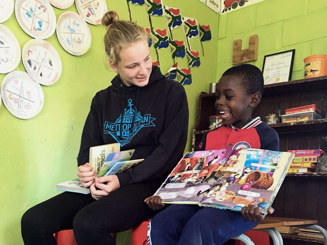 Ein Kind liest Bücher mit einer Freiwilligen