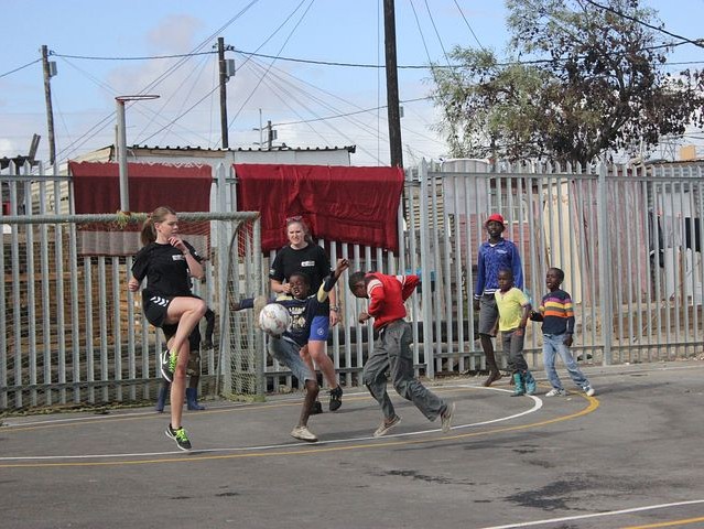 Freiwillige spielen Fußball mit südafrikanischen Kindern im Sportprojekt von SAVE