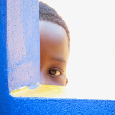 child peaking behind a blue wall