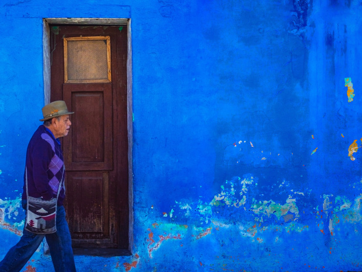 Mann läuft an einem Haus mit Tür und blauer Fassade vorbei