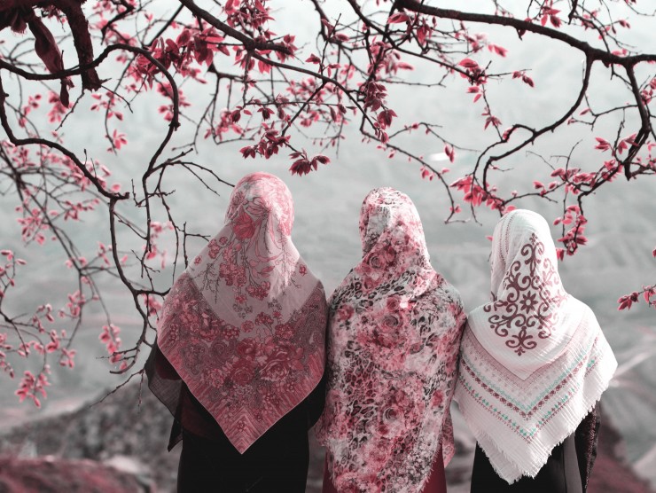 Drei Frauen mit blumigen Kopftüchern blicken in die Berge
